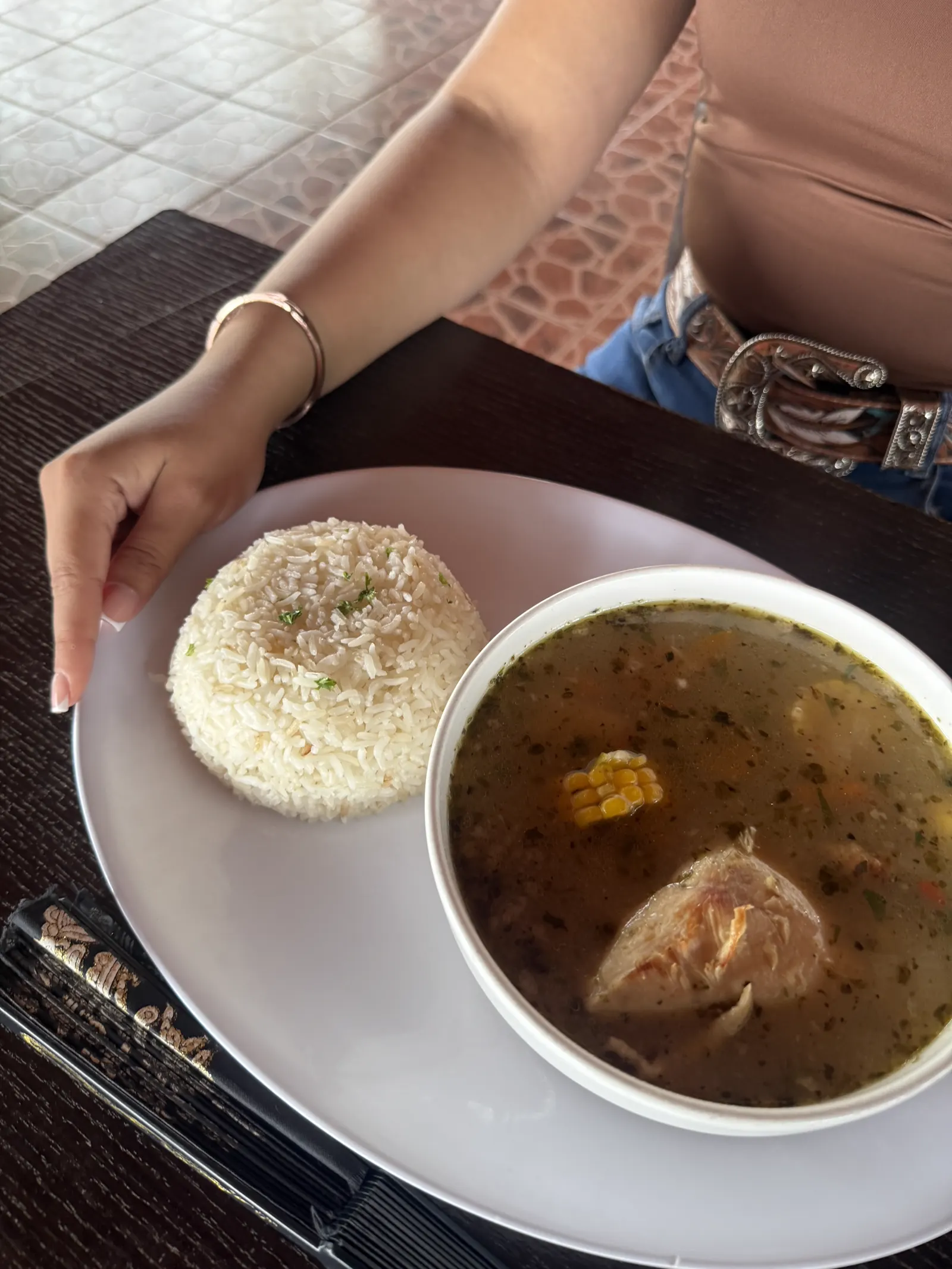 Vista superior de una sopa con maíz y pollo, servida junto a arroz blanco