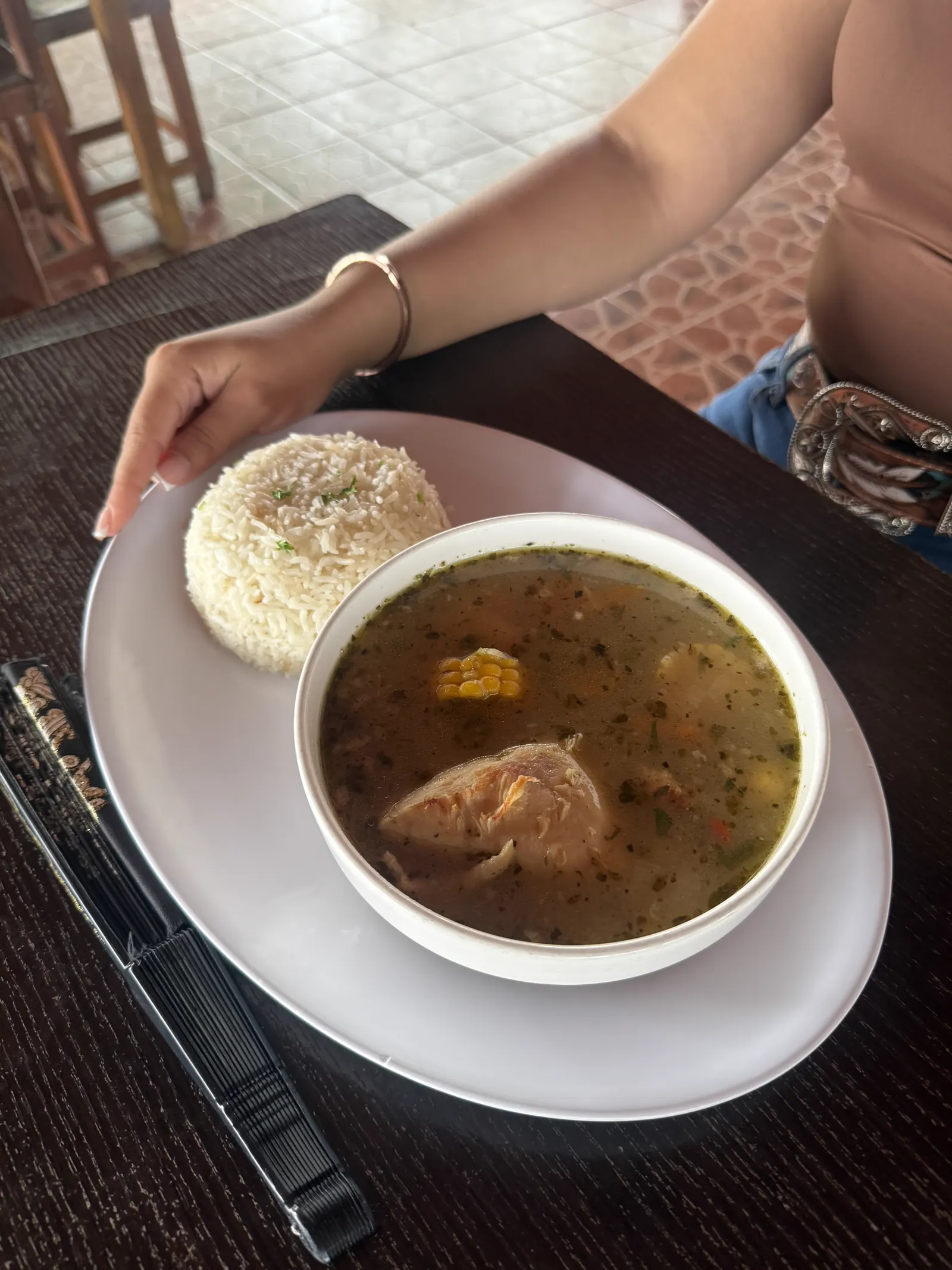 Sopa de gallina con maíz servida junto a arroz blanco, vista desde arriba