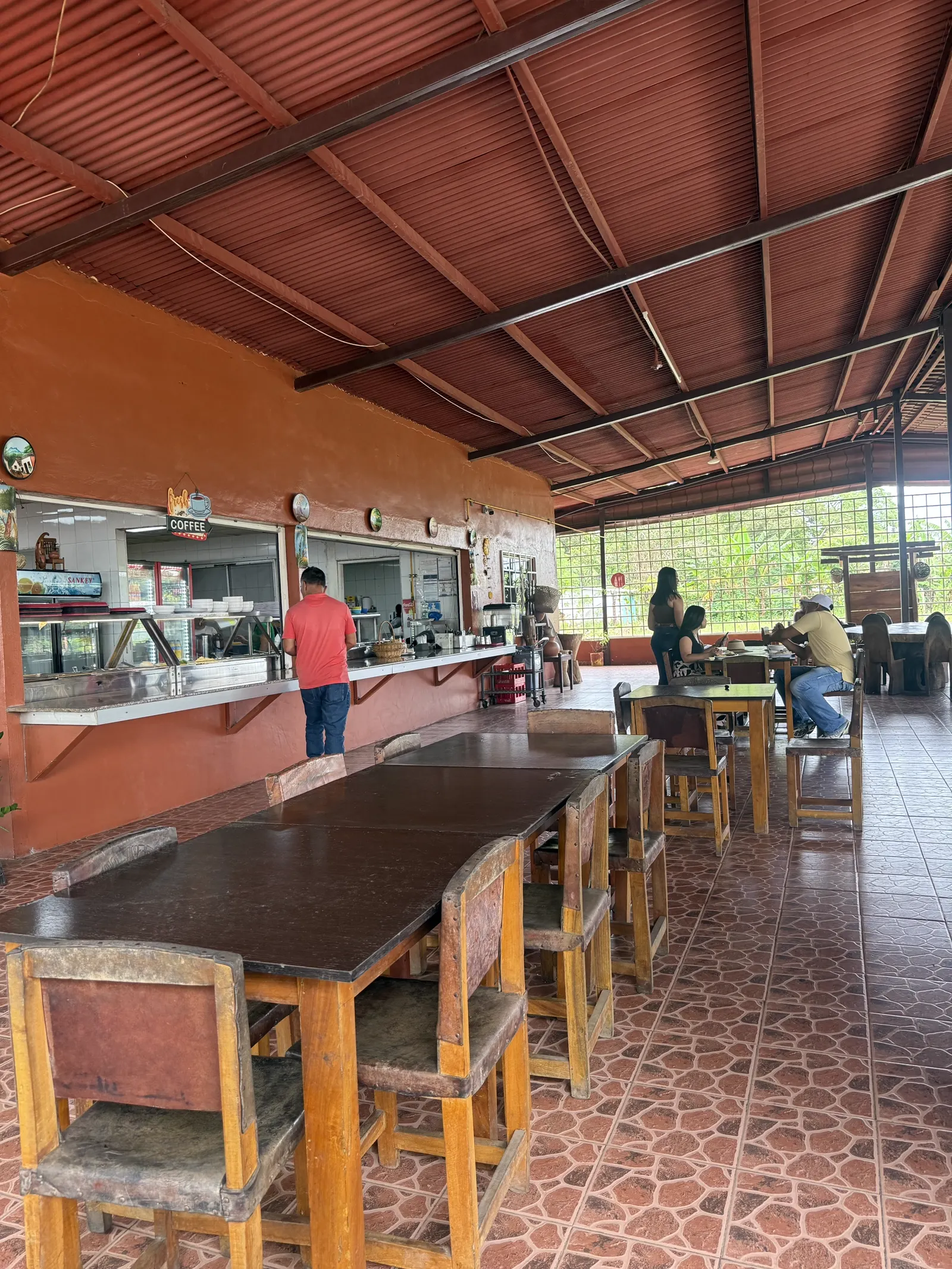 Barra de despacho de la cocina con letrero Fresh Coffee y mesas del comedor