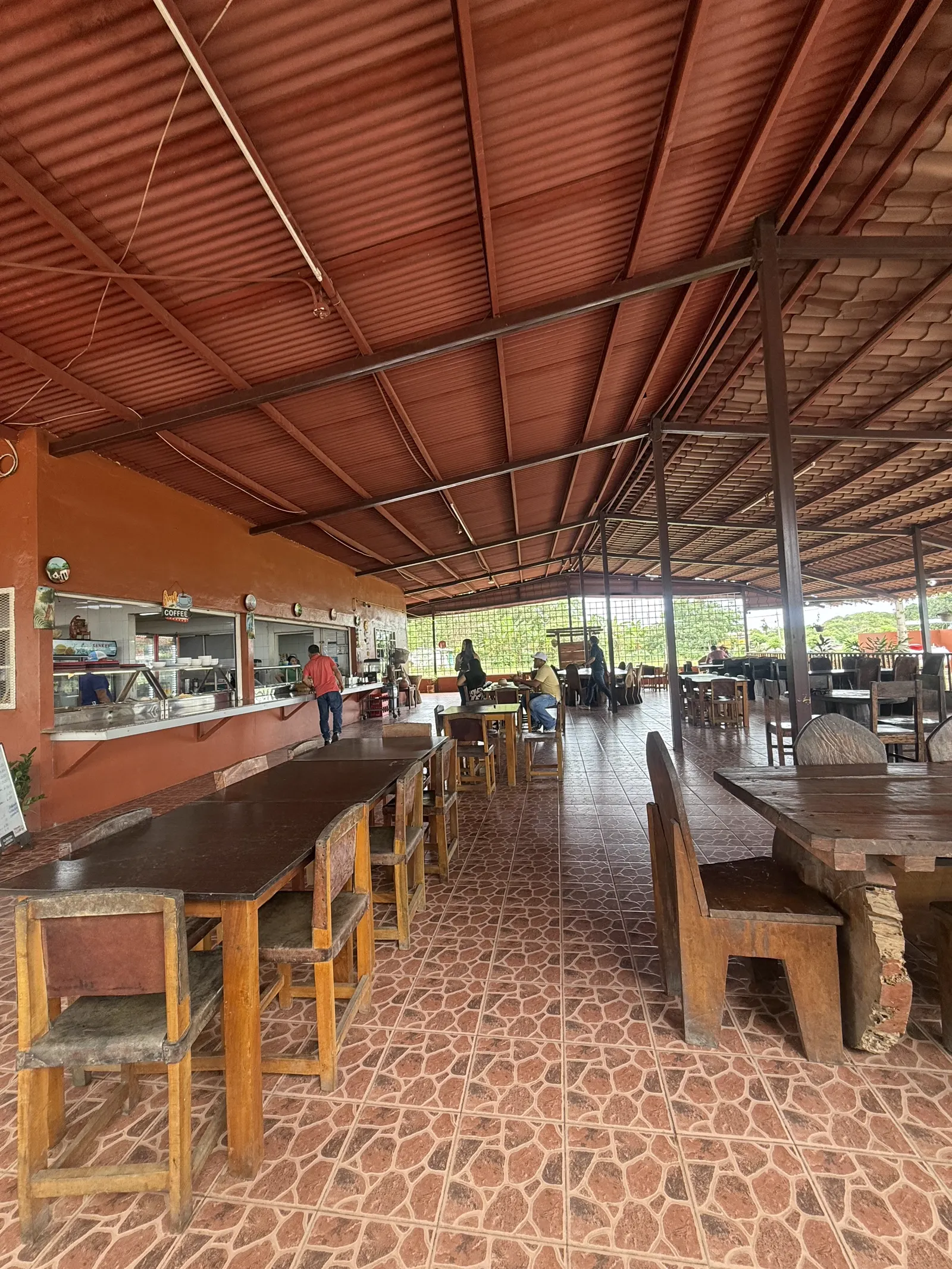 Comedor con mesas de madera junto a la barra de despacho de la cocina
