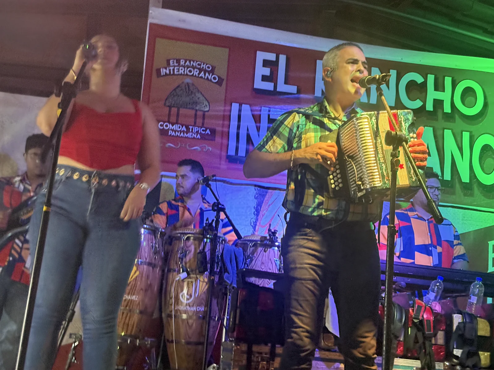 La cantante y el acordeonista de la orquesta en la tarima, con el banner de El Rancho Interiorano — Comida Típica Panameña detrás